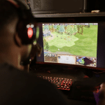A man wearing headset looking at gaming screen
