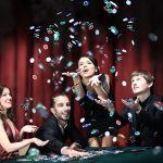 Image of four people enjoying a winning game of cards in a casino, casino chips thrown into the air. Best Casino Games for Real Money