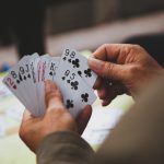 Closeup photo of a man holding a hand of bridge with 13 cards for an article titled Bridge Strategies that Separate the Pros from the Amateurs