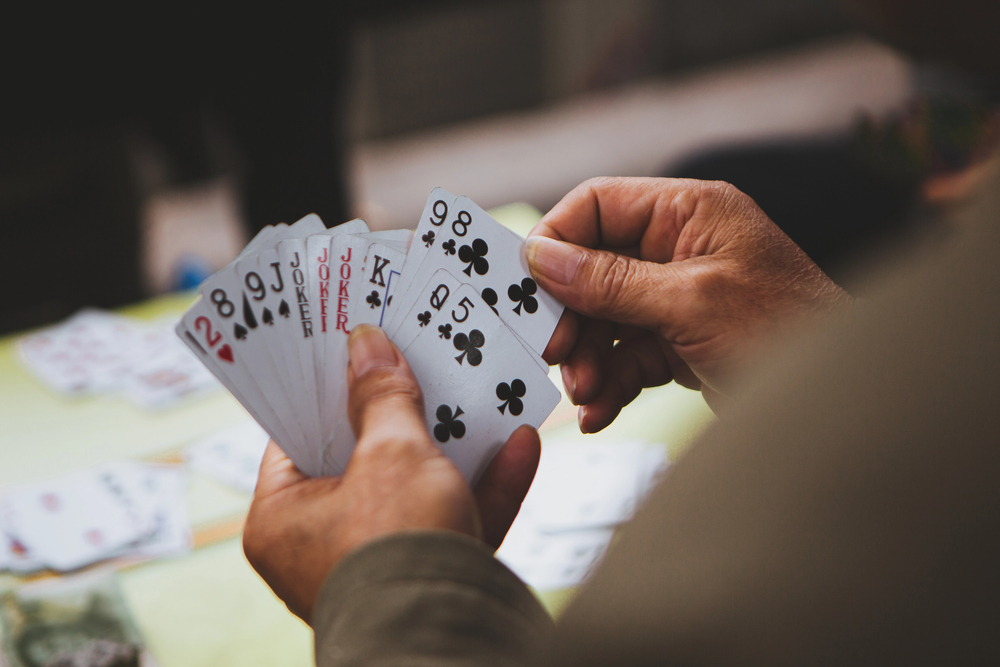 Closeup photo of a man holding a hand of bridge with 13 cards for an article titled Bridge Strategies that Separate the Pros from the Amateurs