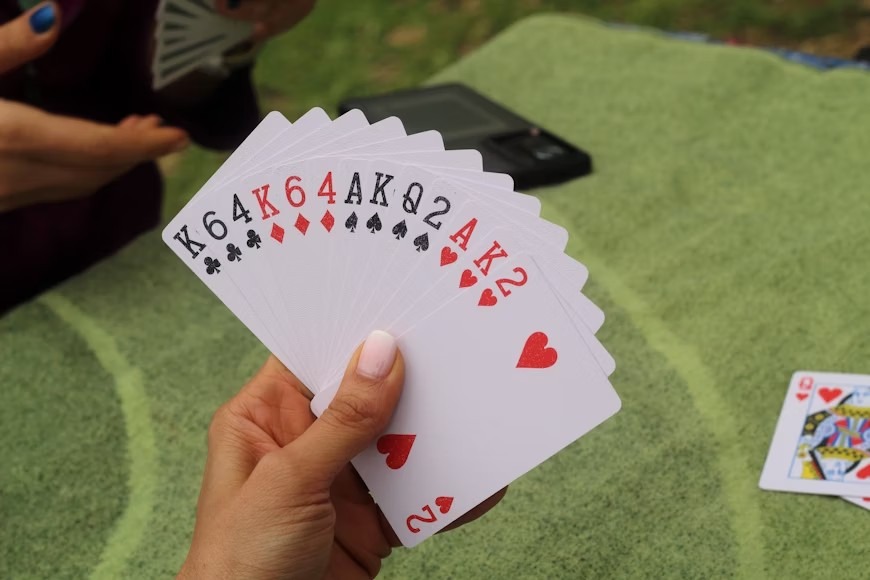 Imagine of a bridge hand with 13 cards, set against a green background. For an article titled How Stablecoins Can Streamline Bridge Tournaments