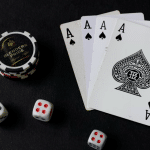 Four aces, poker chips, and dice on a dark table surface