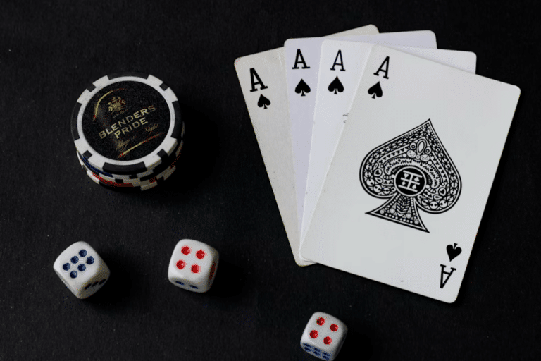 Four aces, poker chips, and dice on a dark table surface