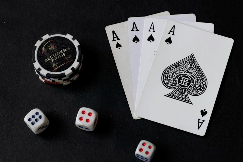 Four aces, poker chips, and dice on a dark table surface
